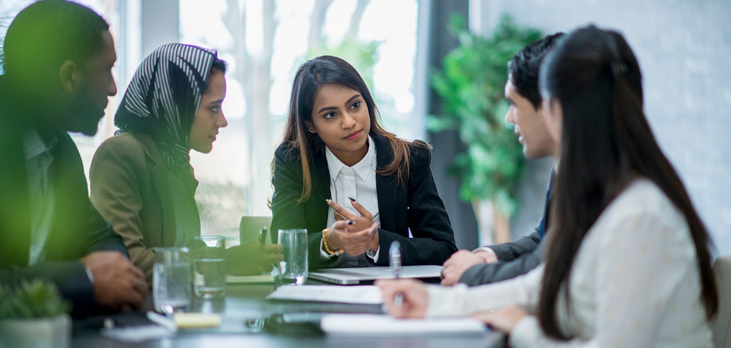 Three business women and two business men at a meeting.