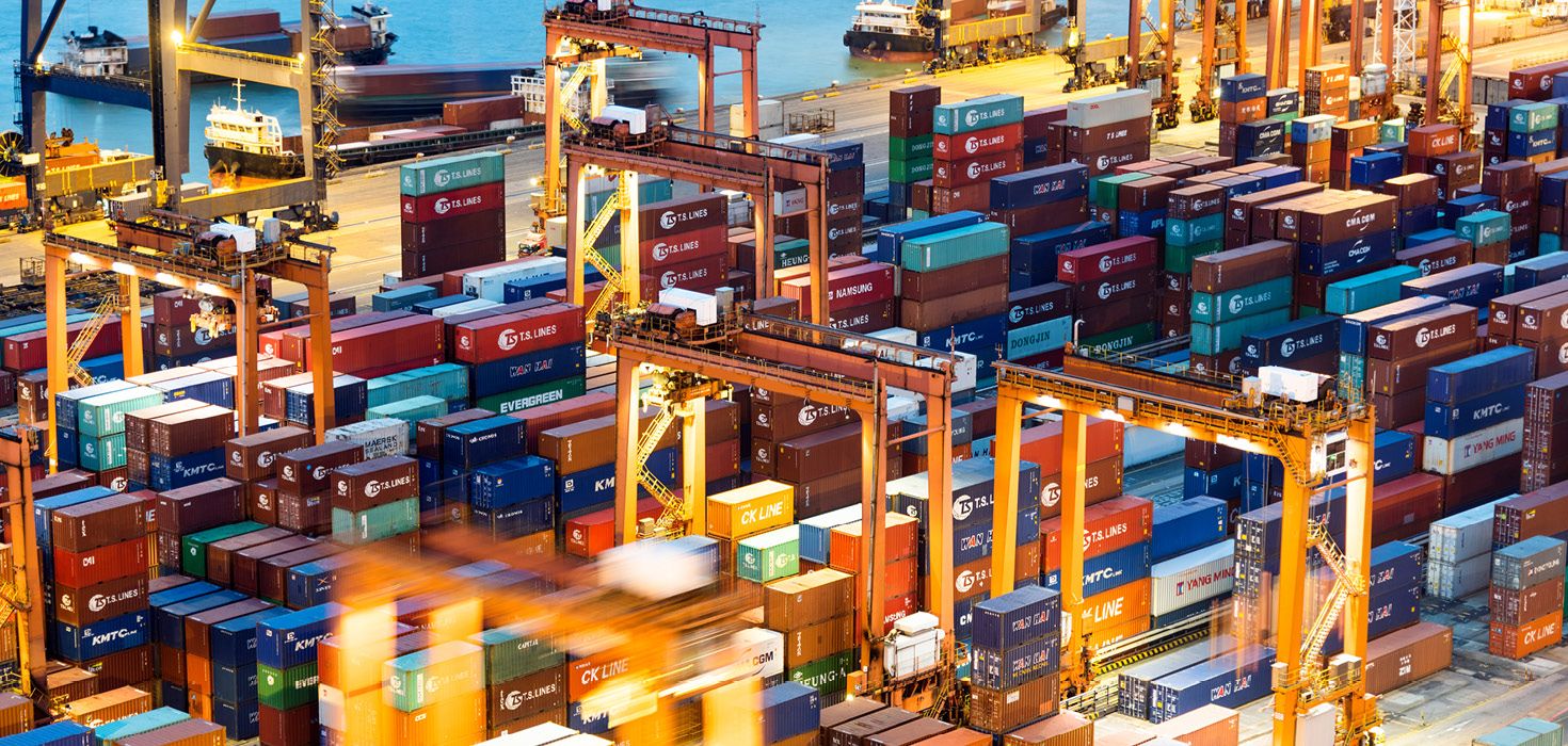 Stacked shipping containers on a dock at dusk. 