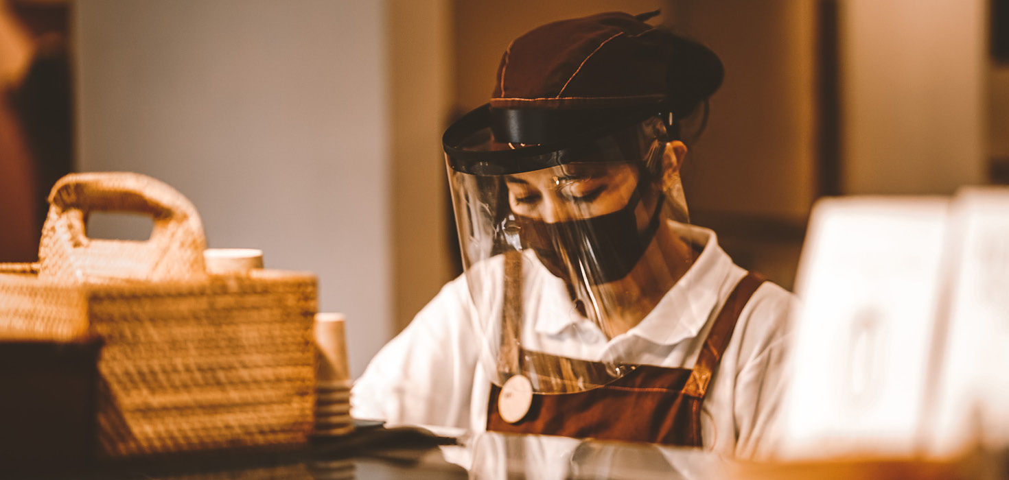 Woman in apron wearing face sheild