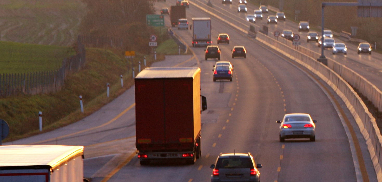 Several cars drive down a wide highway.