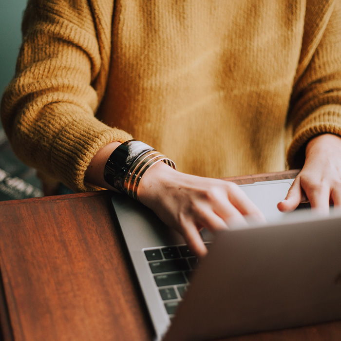 Woman in orange sweater working on computer