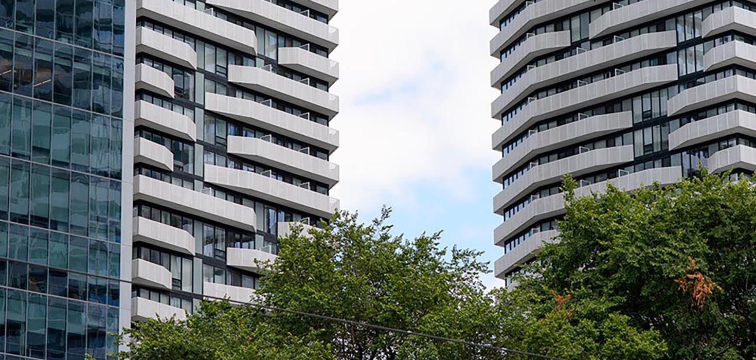 Two condo towers jut up into the sky on a sunny day.