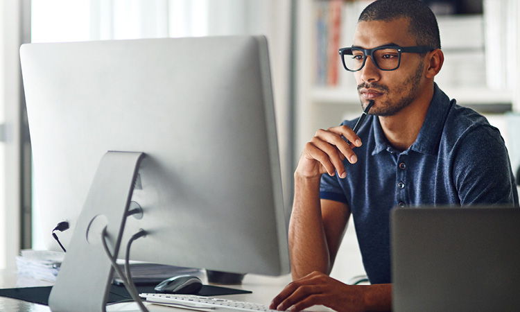 Man with glasses looking at computer screen. 