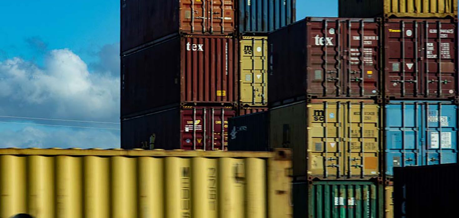 Shipping containers stacked on top of each other with a blue sky in the background.