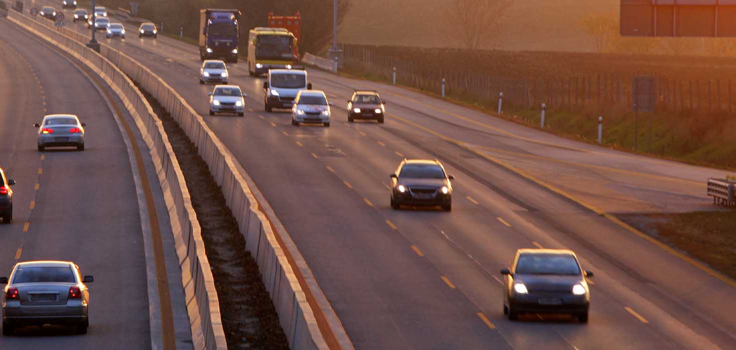 Several cars drive down a wide highway. 