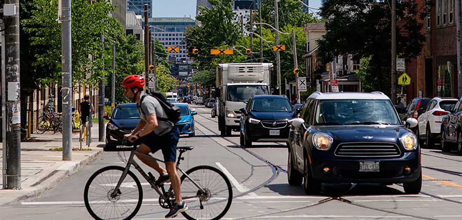 A busy downtown intersection filled with cars and a cyclist. 